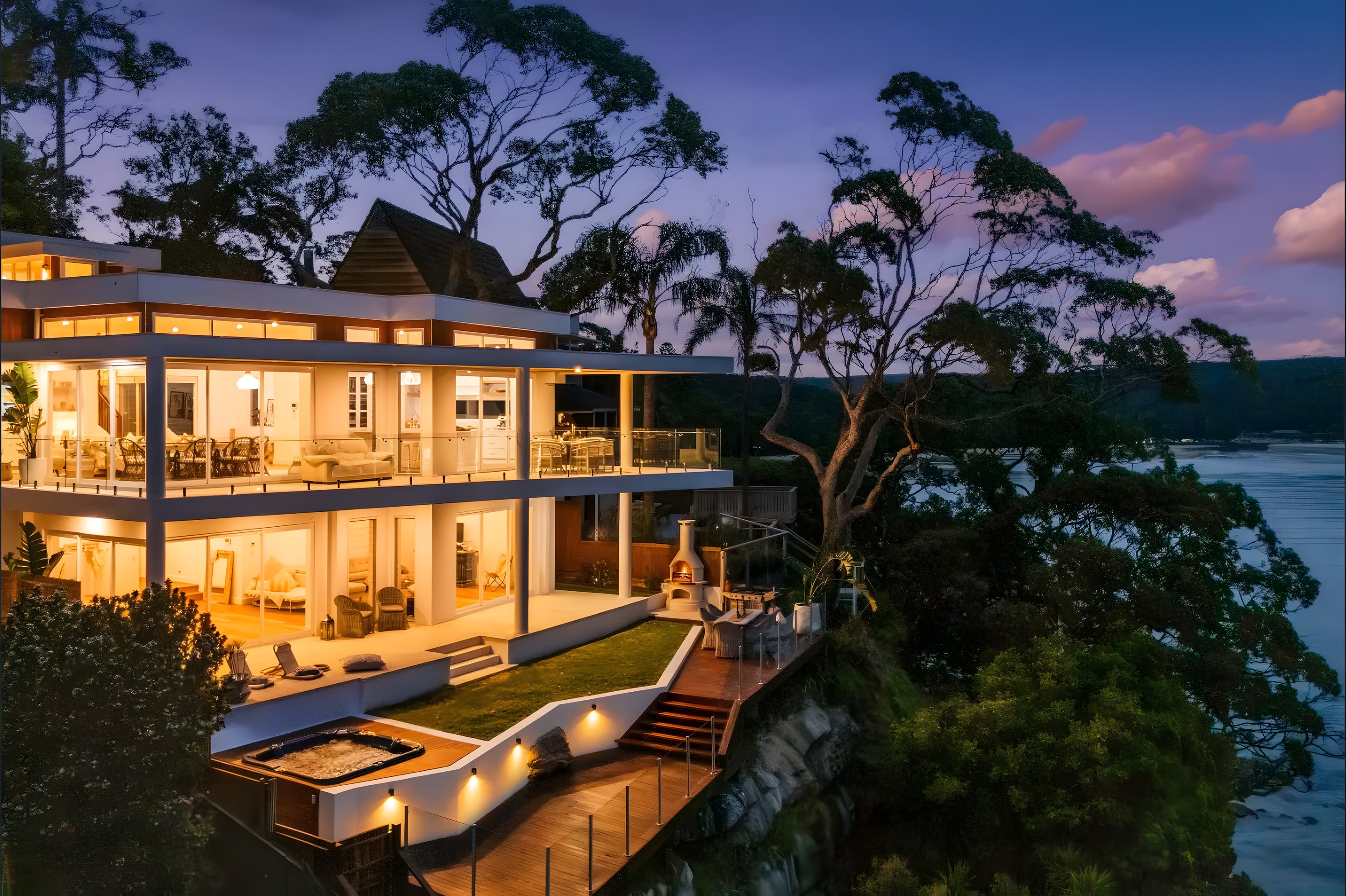 A clifftop home lit at dusk above the water